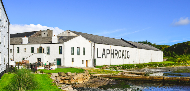 The Laphroaig distiller in Scotland. Green grass and old buildings next to a stream