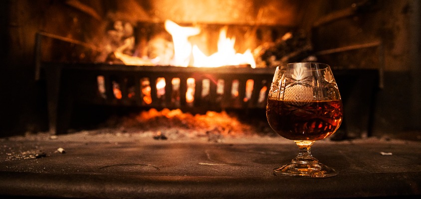 A glass of cognac in front of a warm winter log fire